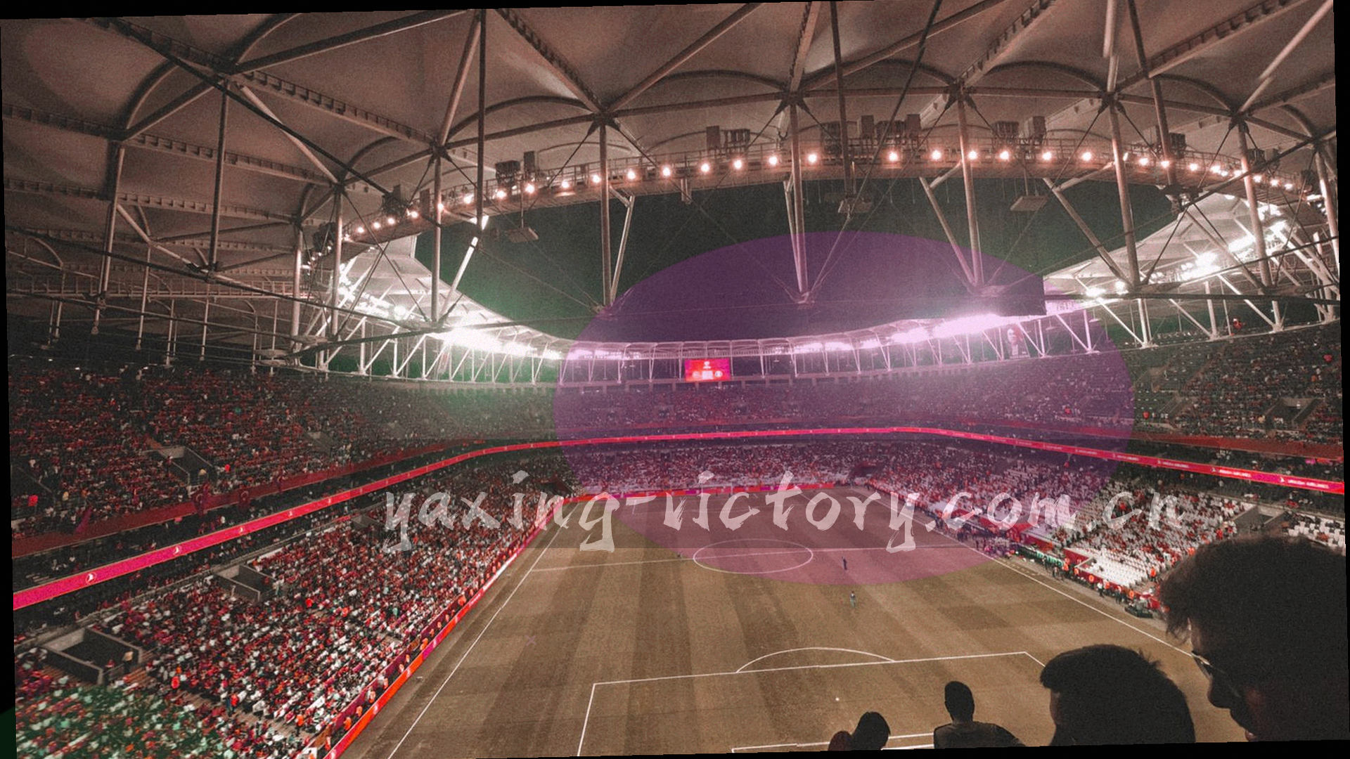 夜色中的体育场看台，聚光灯扫过层层观众席